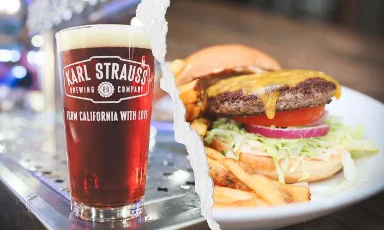 a glass of beer next to a burger and fries