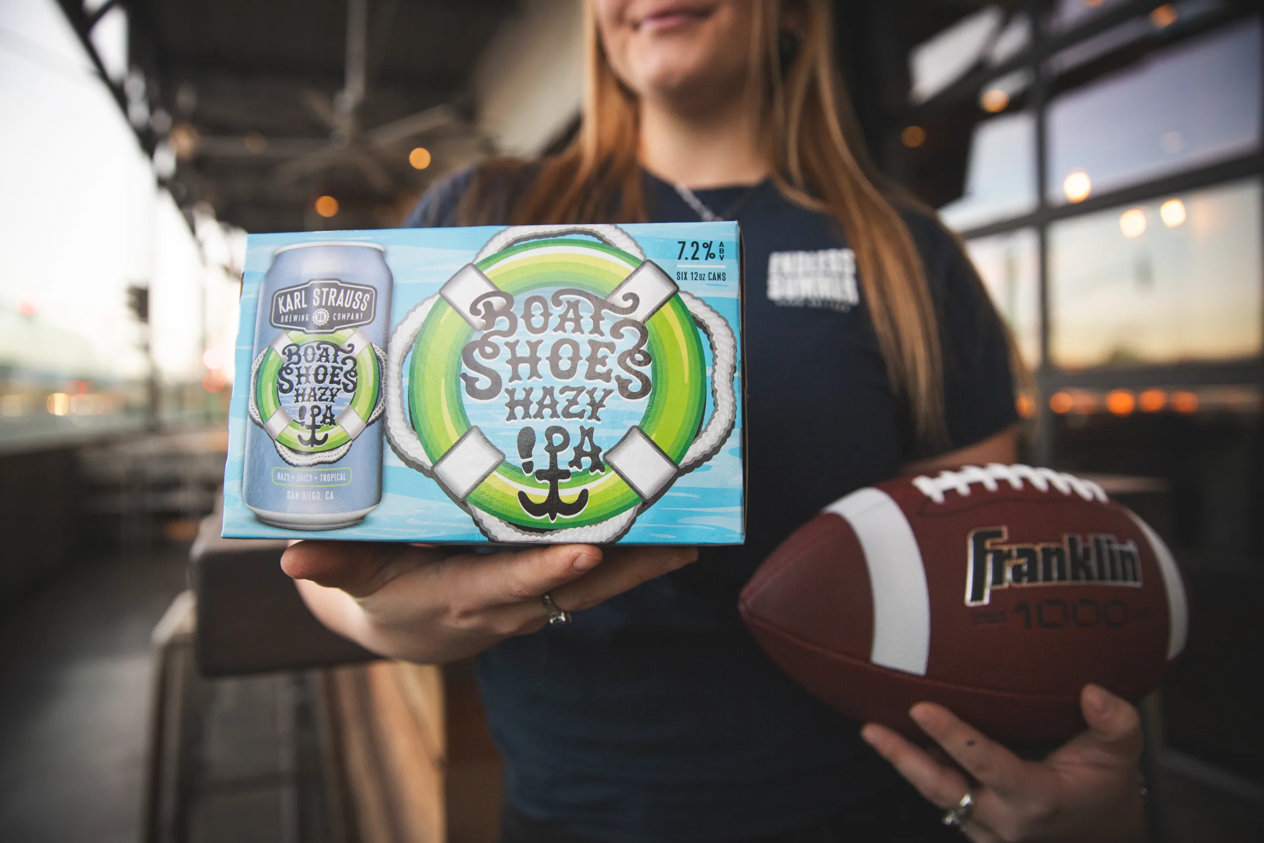 a woman holding a box of beer and a football